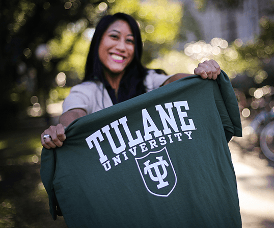 Transfer student holding up Tulane University t-shirt and smiling - Tulane SoPA