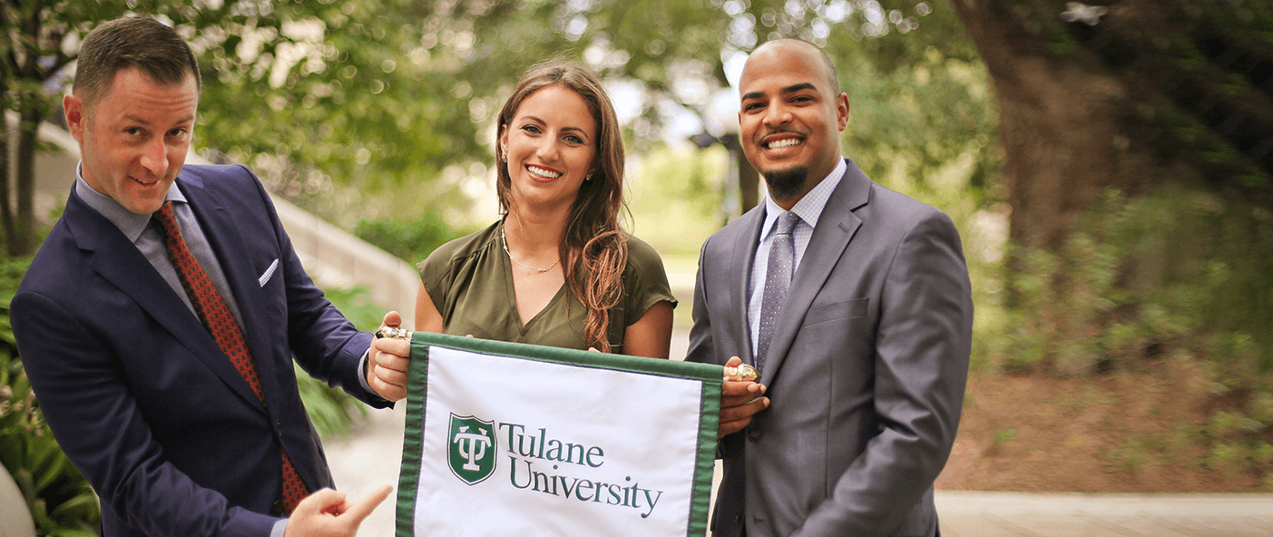 Transfer Students ans professor smiling and holding up a Tulane University banner - Tulane SoPA