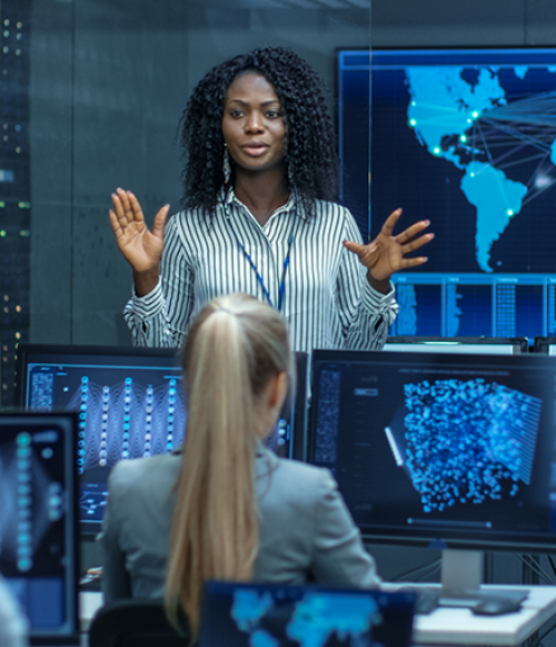 Woman standing in front of world map speaking to colleagues - Tulane School of Professional Advancement