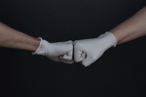 Ready about PPE best practices Two fists bumping while wearing medical gloves