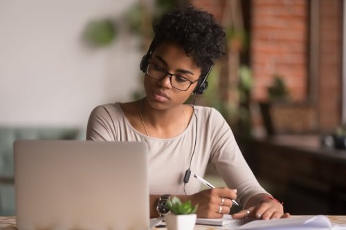 Get the most out of your online classes A student listening to headphones while taking notes off a laptop