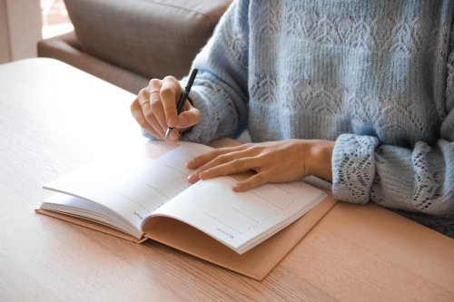 Person writing in notebook at a desk - Tulane School of Professional Advancement