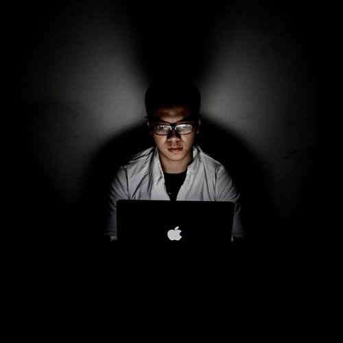 Learn about the dark web A person using a laptop in the dark