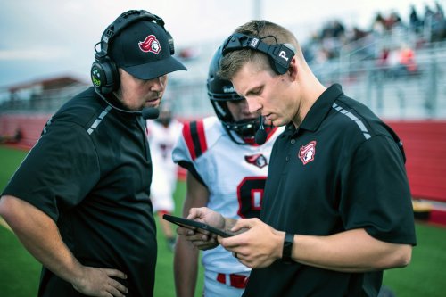Two sports professionals wearing headsets and analyzing football