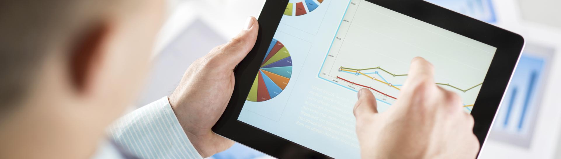 A business person looking at charts and graphs on a tablet