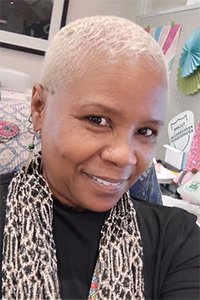 Close-up photograph of a Black woman with short blonde hair and a leopard print scarf.