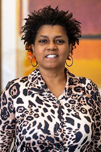 Woman with natural hair and leopard print shirt smiles at camera.