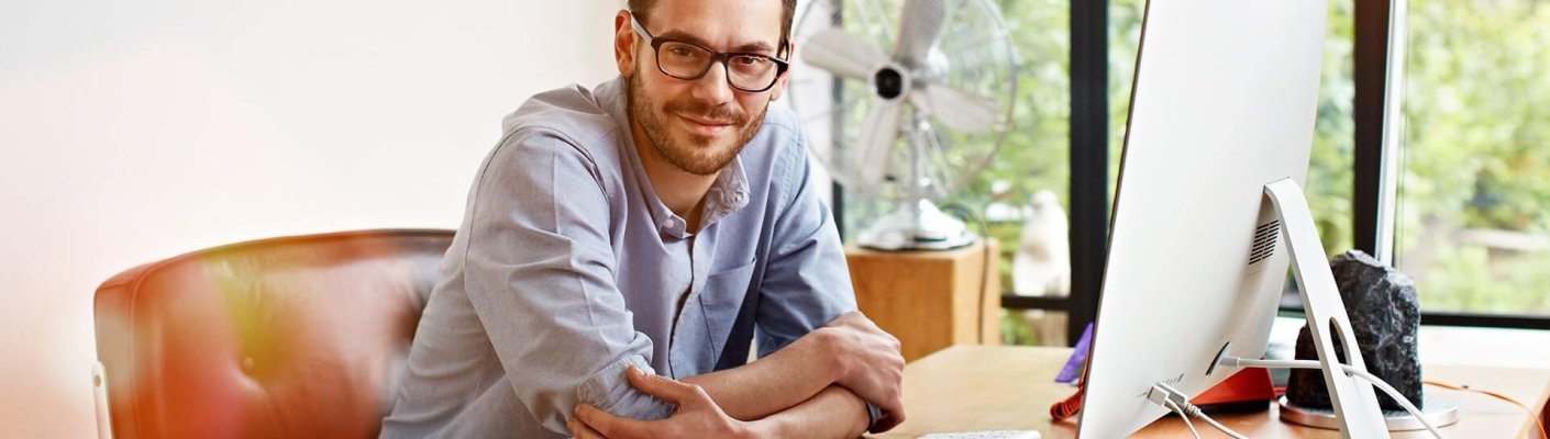 A guy smiling at his desk