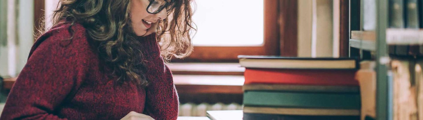 A woman studying next to a stack of books