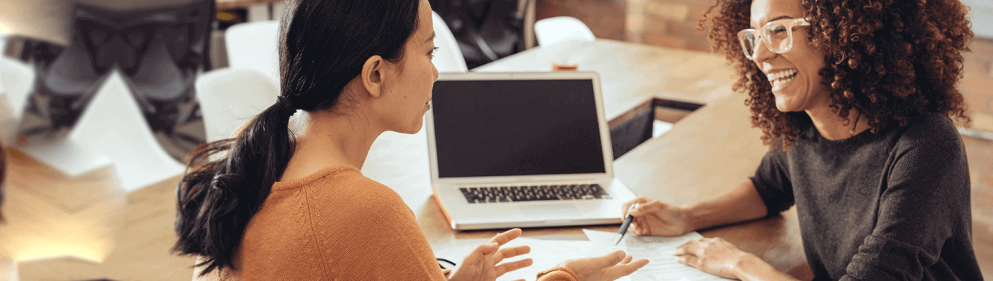 Two business professionals talking in front of a laptop