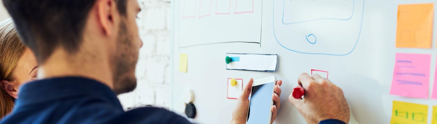 Two people using a whiteboard for organization
