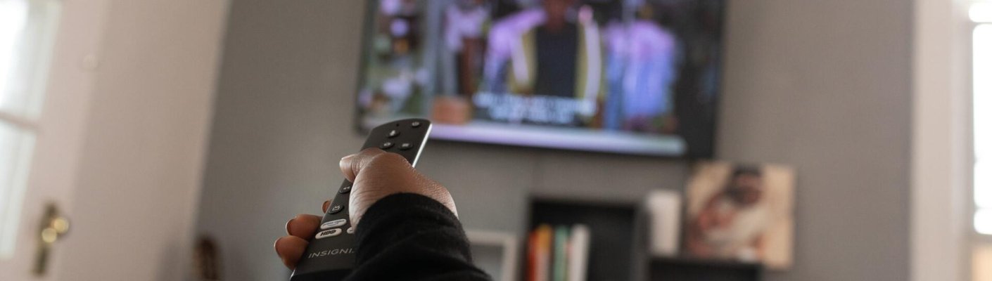 A person using a remote to change the channel on a TV