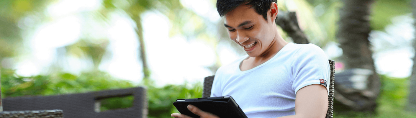 A person sitting outside and looking at a tablet