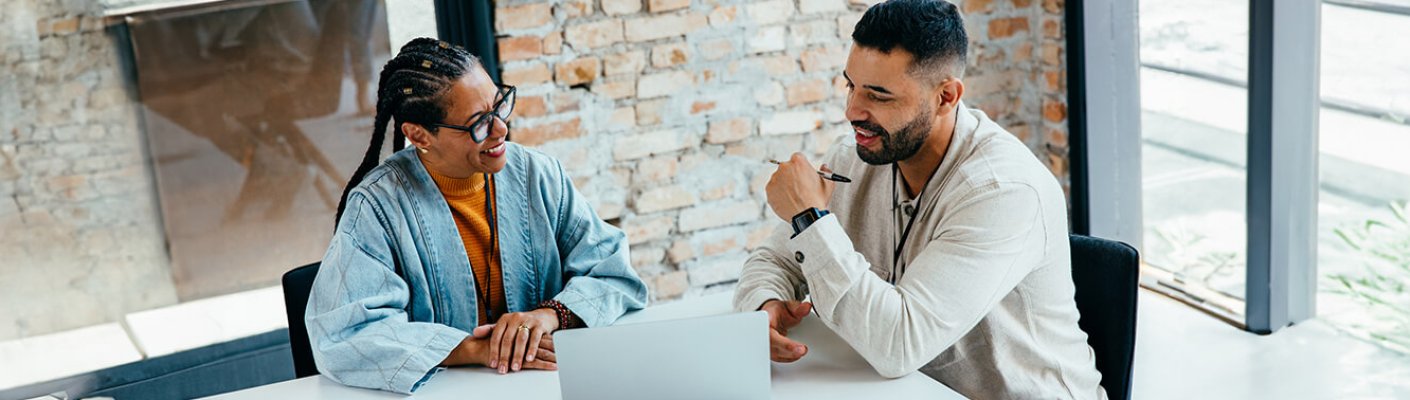 Two people discussing in front of a laptop