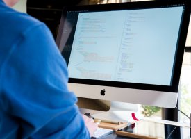 A person writing code on their desktop computer