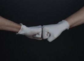 Two fists bumping while wearing medical gloves