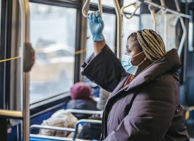 A woman wearing a mask and gloves on a bus