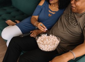 A couple on a couch eating popcorn