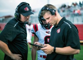 Two sports professionals wearing headsets and analyzing football