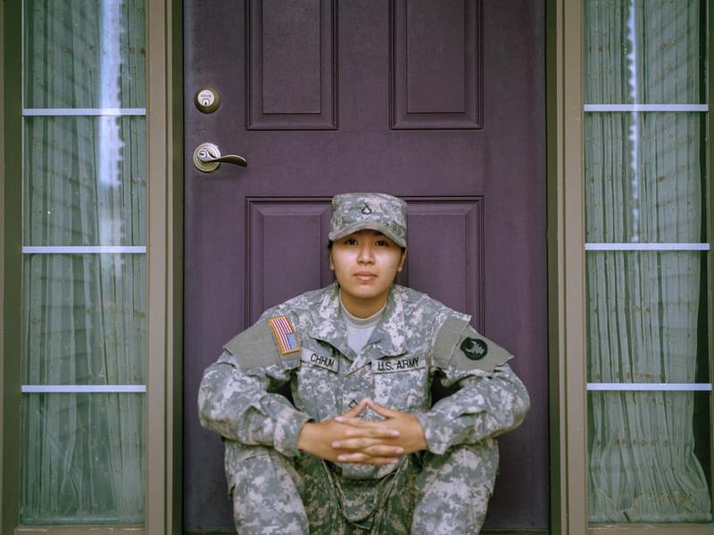 A woman in army cammies sitting in front of a door